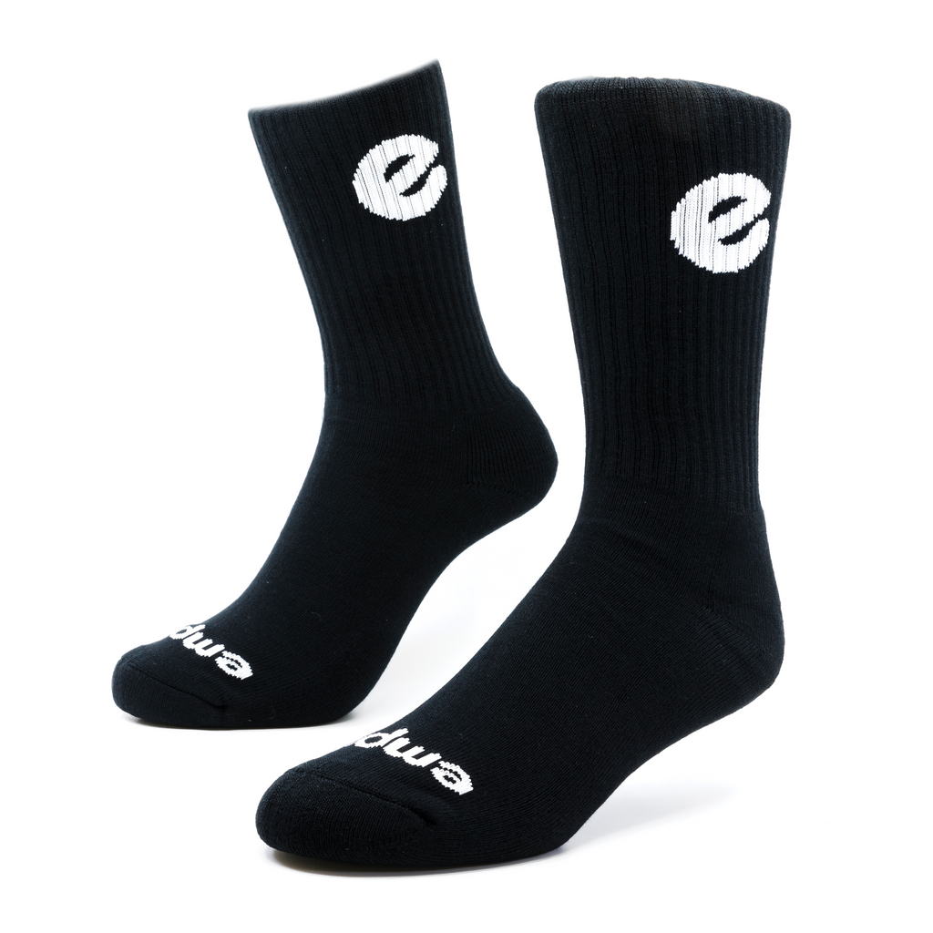 a pair of black socks that with a large white letter knitting into the ribbing and near the toe