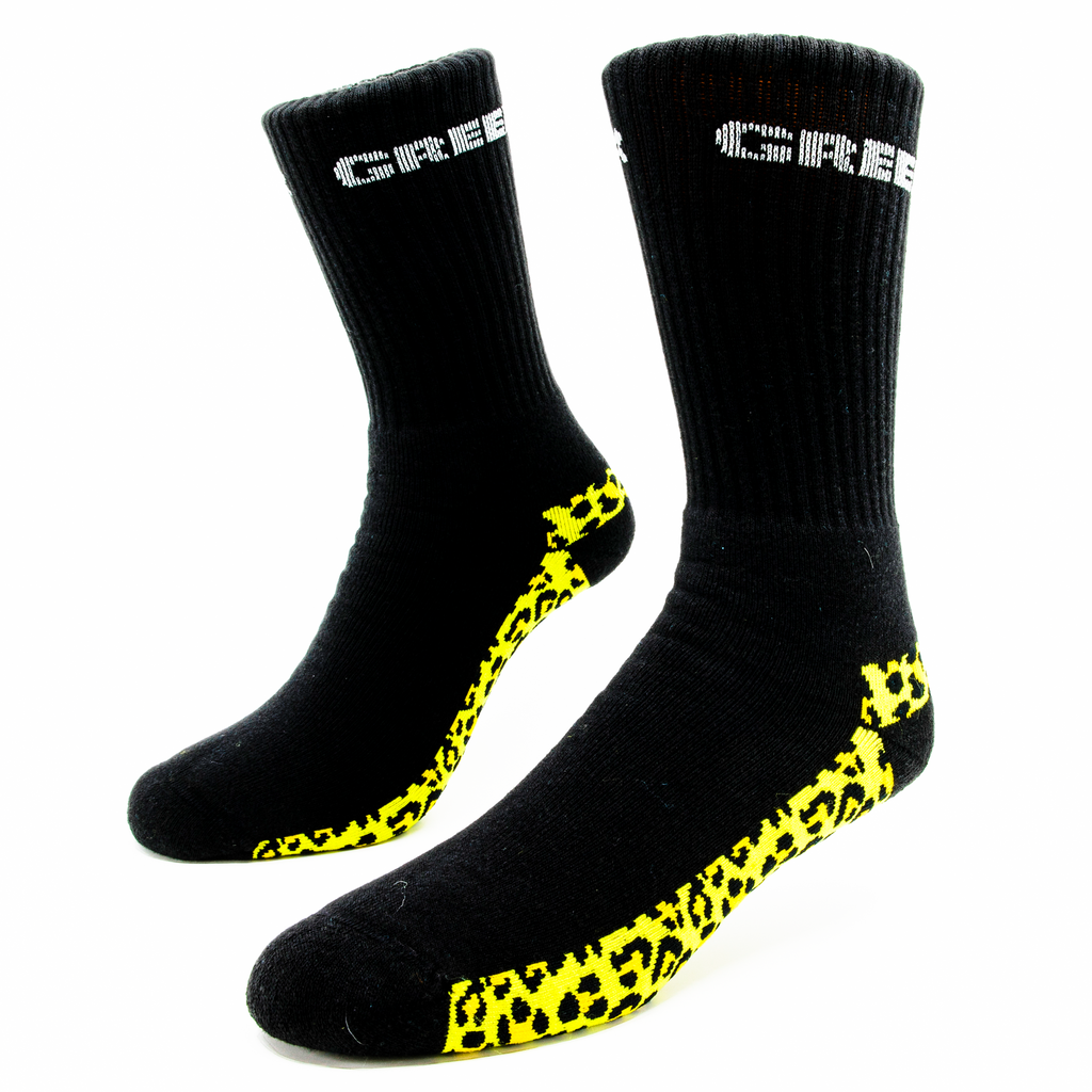 A pair of black socks with a bright yellow cheetah print on the bottom of the foot