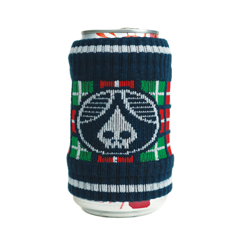 A can covered with a knitted drink sleeve that depicts a skull with a funky red and green print